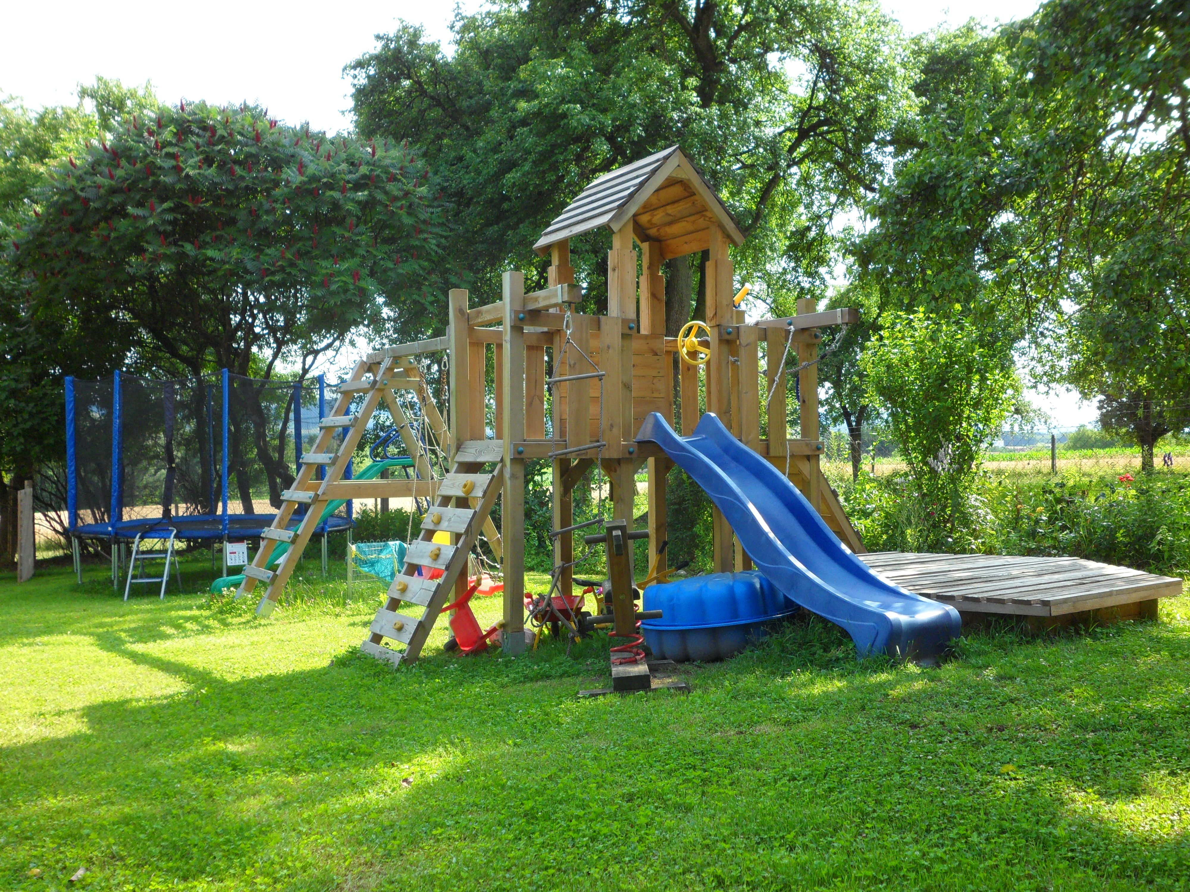 A playground in the garden with climbing frame, slide and trampoline.