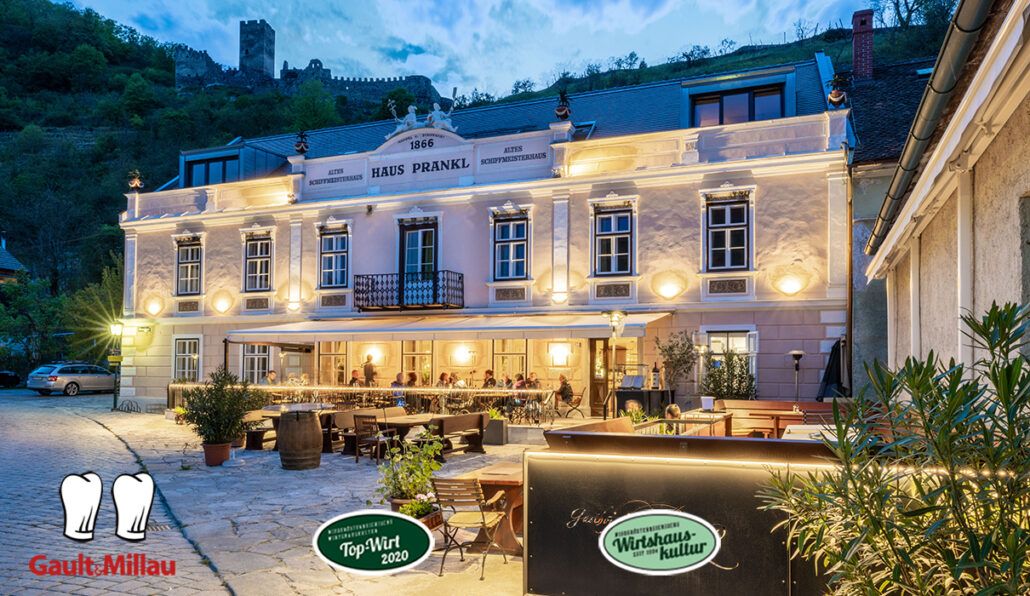 Evening shot of the Gasthof Prankl with illuminated façade and guests on the terrace.