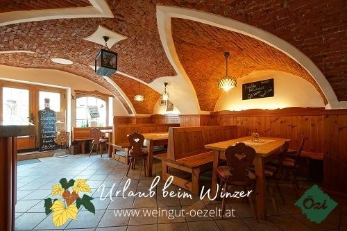 Interior view of a cozy wine tavern with vaulted brick ceiling and wooden furniture.
