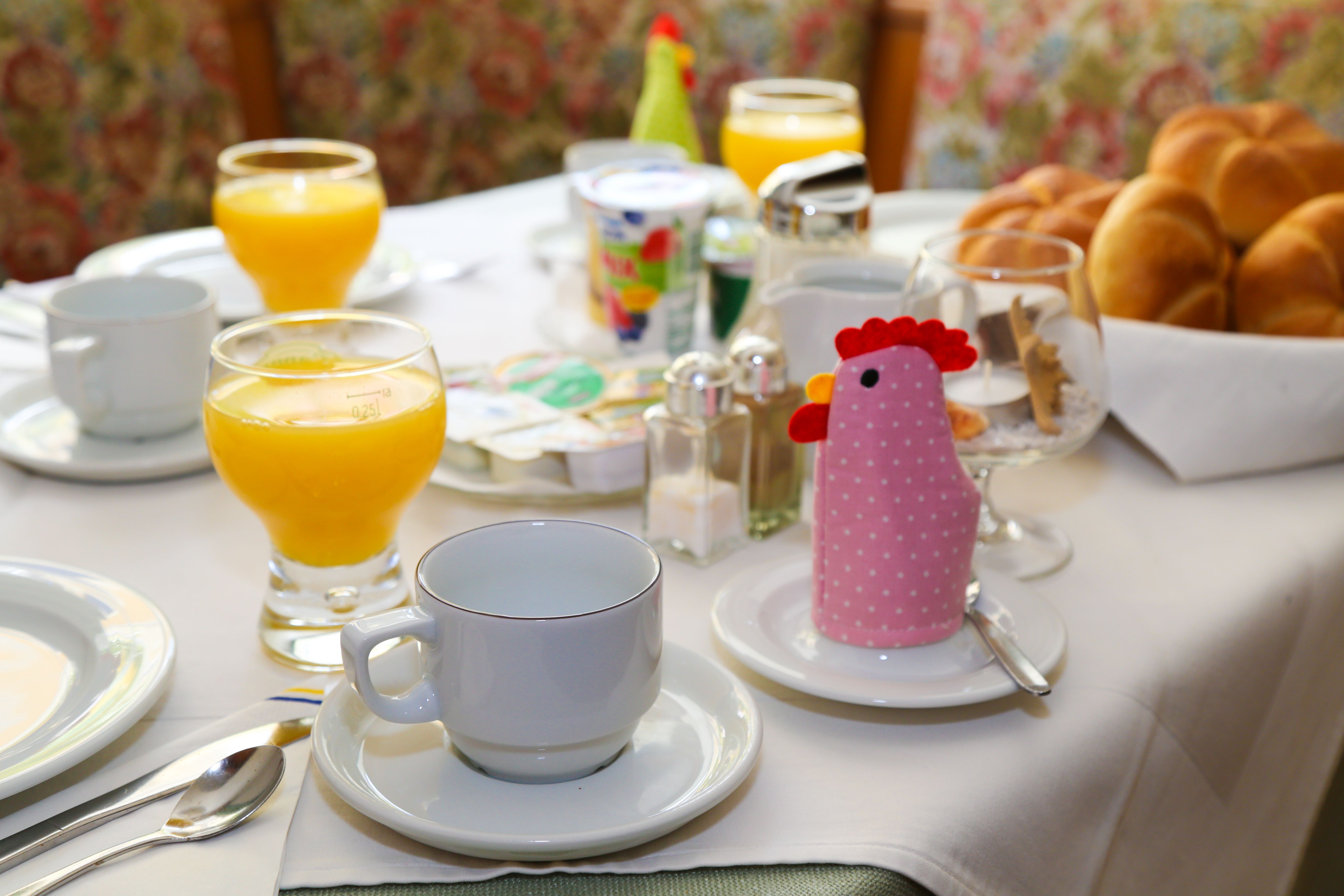Breakfast table with orange juice, bread rolls and cups in a guesthouse.
