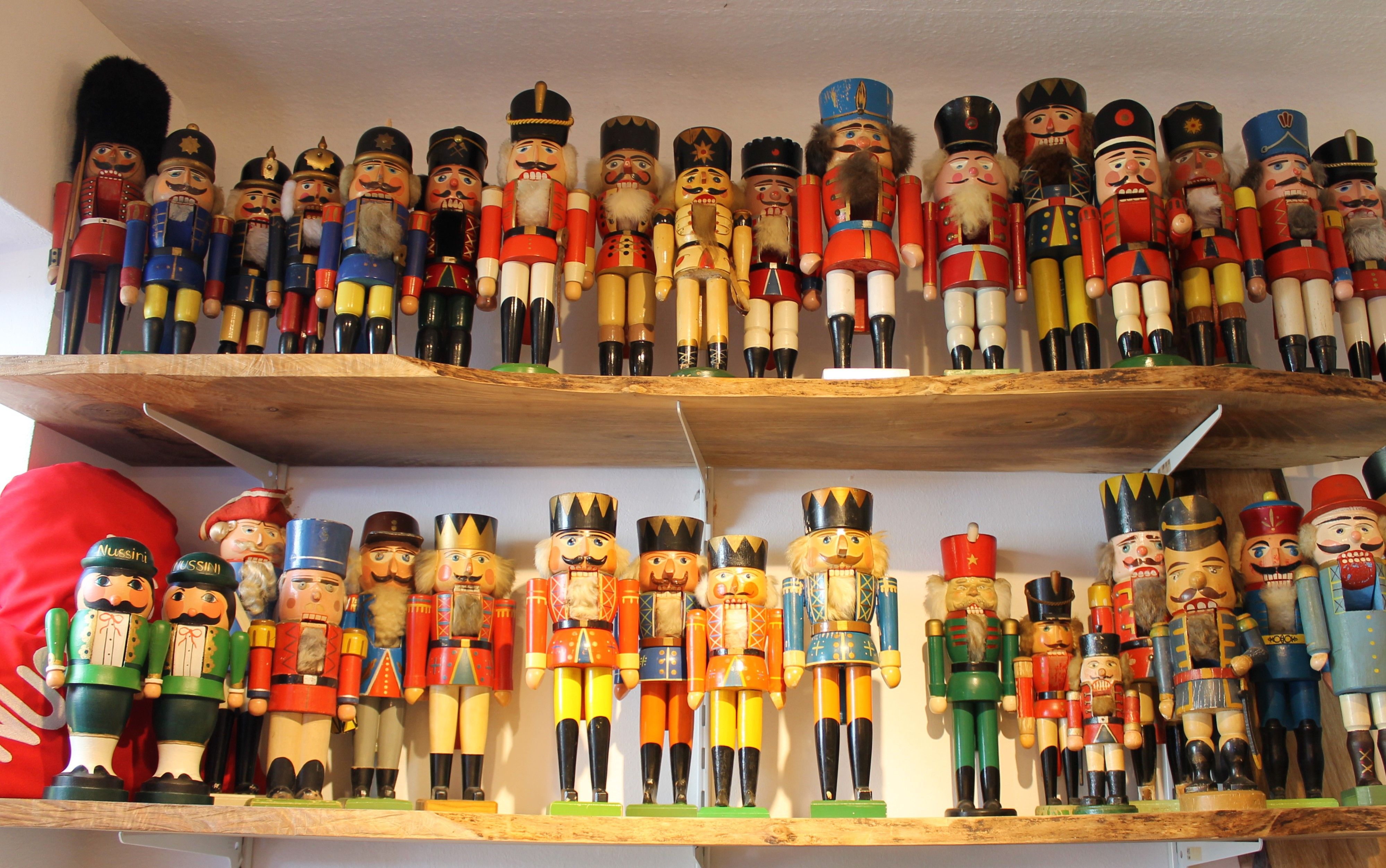 A collection of colorful nutcracker figures on two wooden shelves.
