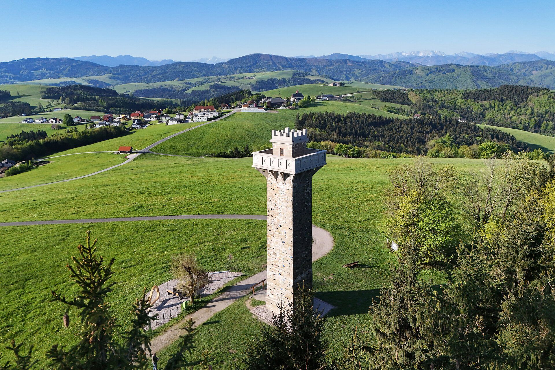 Observation tower in the middle of a green hilly landscape.