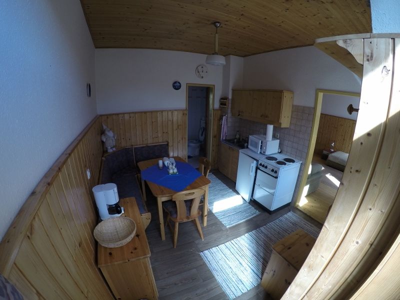 Kitchen-living room in a vacation apartment with wooden furniture, dining table, kitchenette and access to a bedroom.