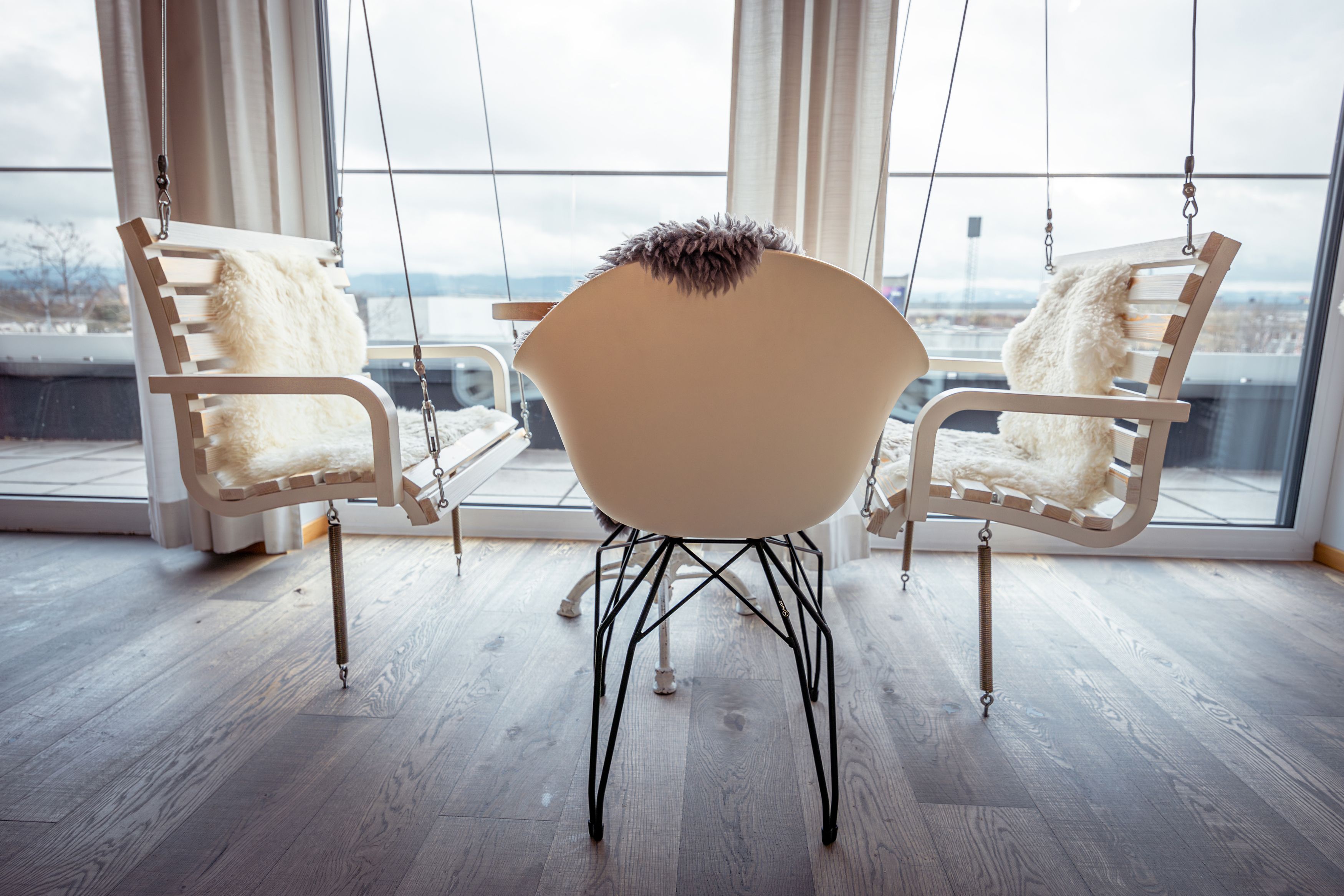 Interior with rocking chairs and a modern chair in front of large windows.
