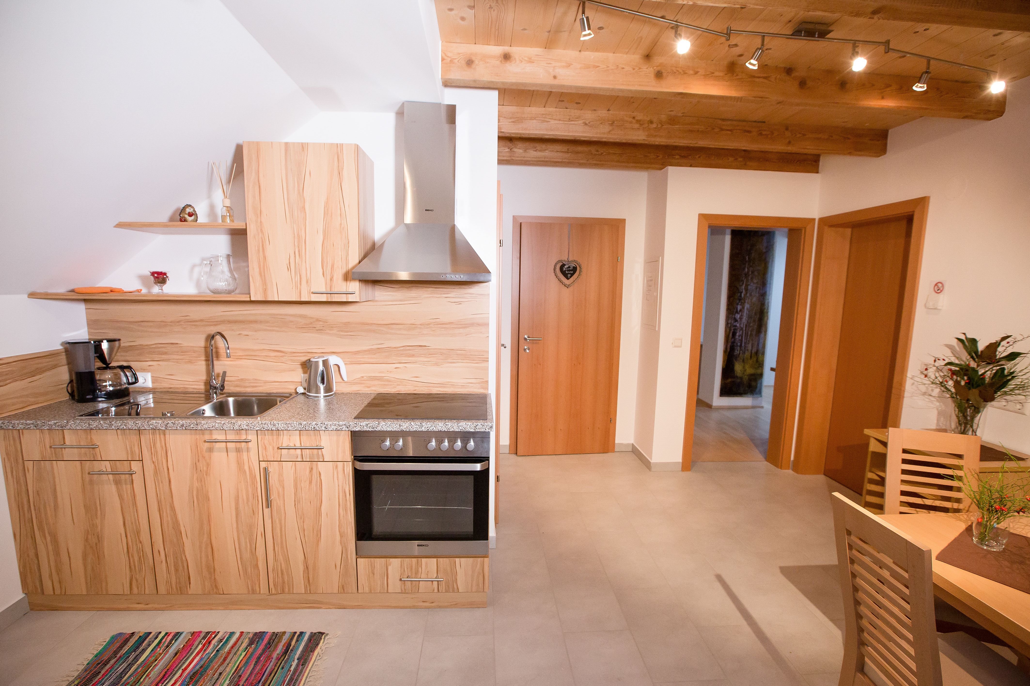 Modern kitchen with wooden decor, dining table and flowers.