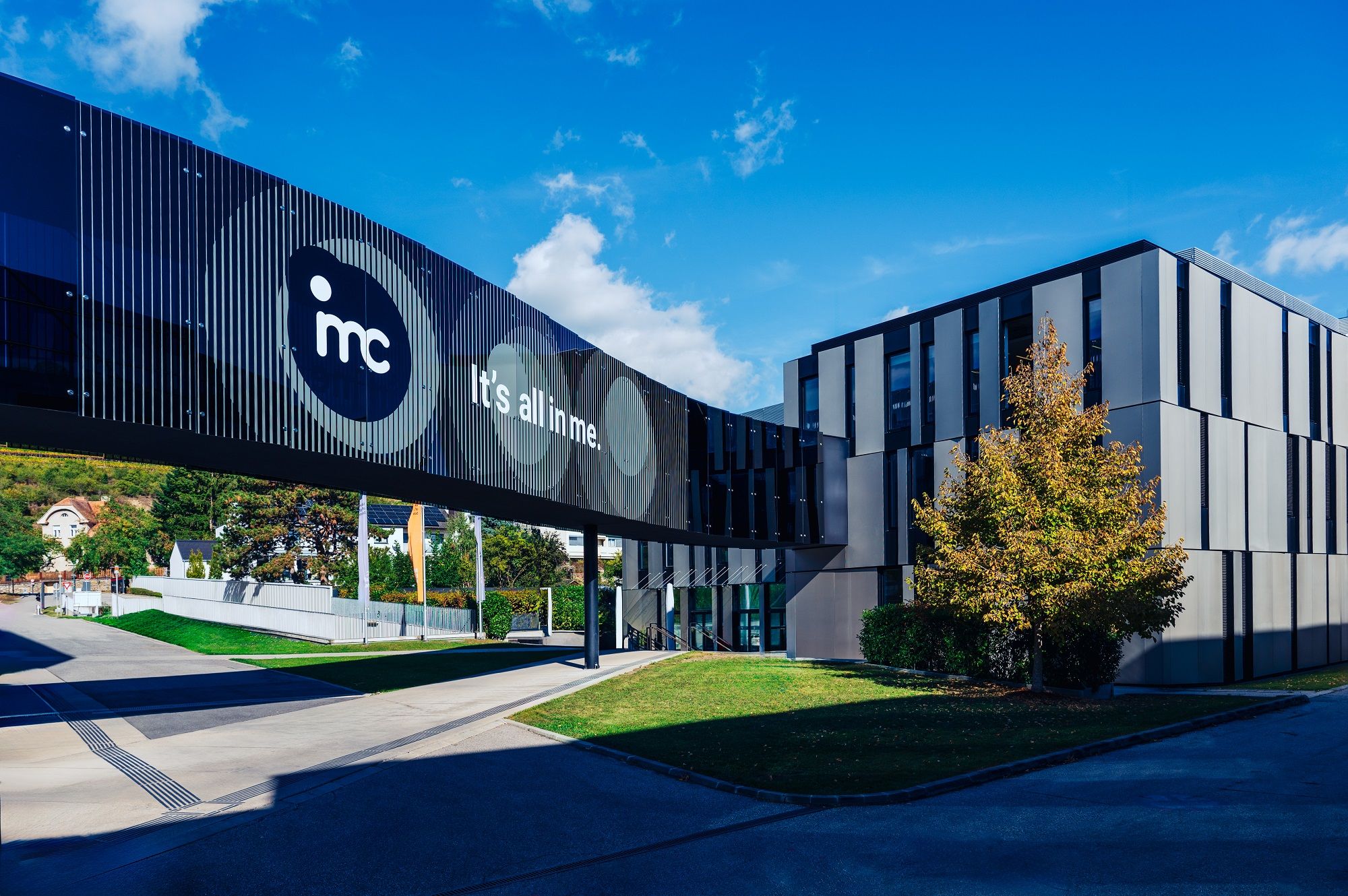 Modern IMC Krems building with glass bridge and 'It's all in me' lettering.