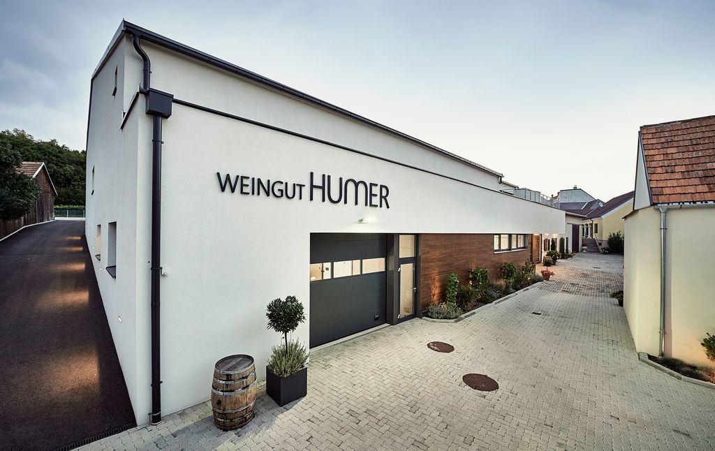 Modern building of the Humer winery with paved courtyard and plants.