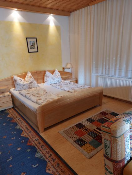 Comfortable guest room with double bed, colorful carpets and wooden furniture.