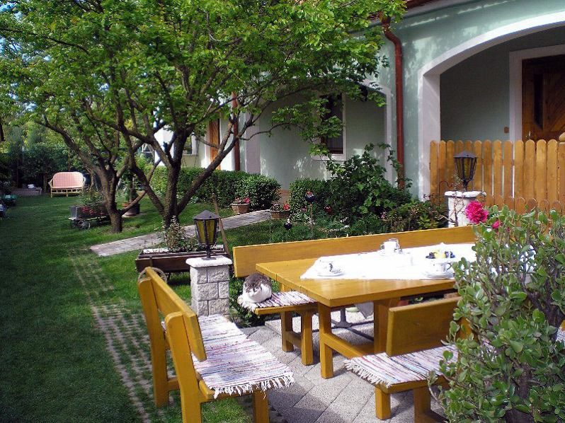 A well-kept garden with wooden furniture, a cat on the bench and a laid table.