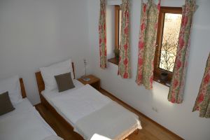 Two single beds in a bright guest room with floral patterned curtains.
