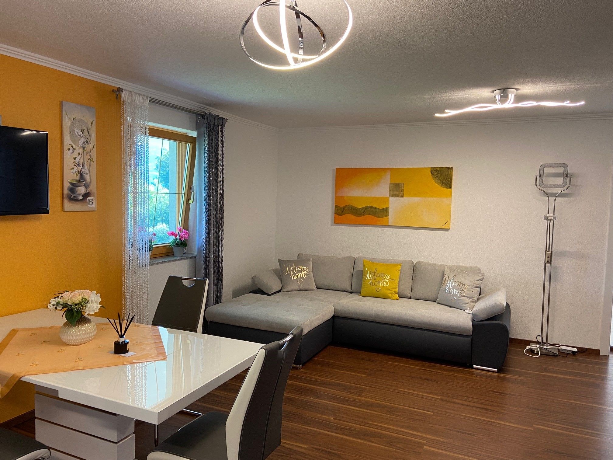 Kitchen-living room with gray pull-out couch, dining table and decorations.