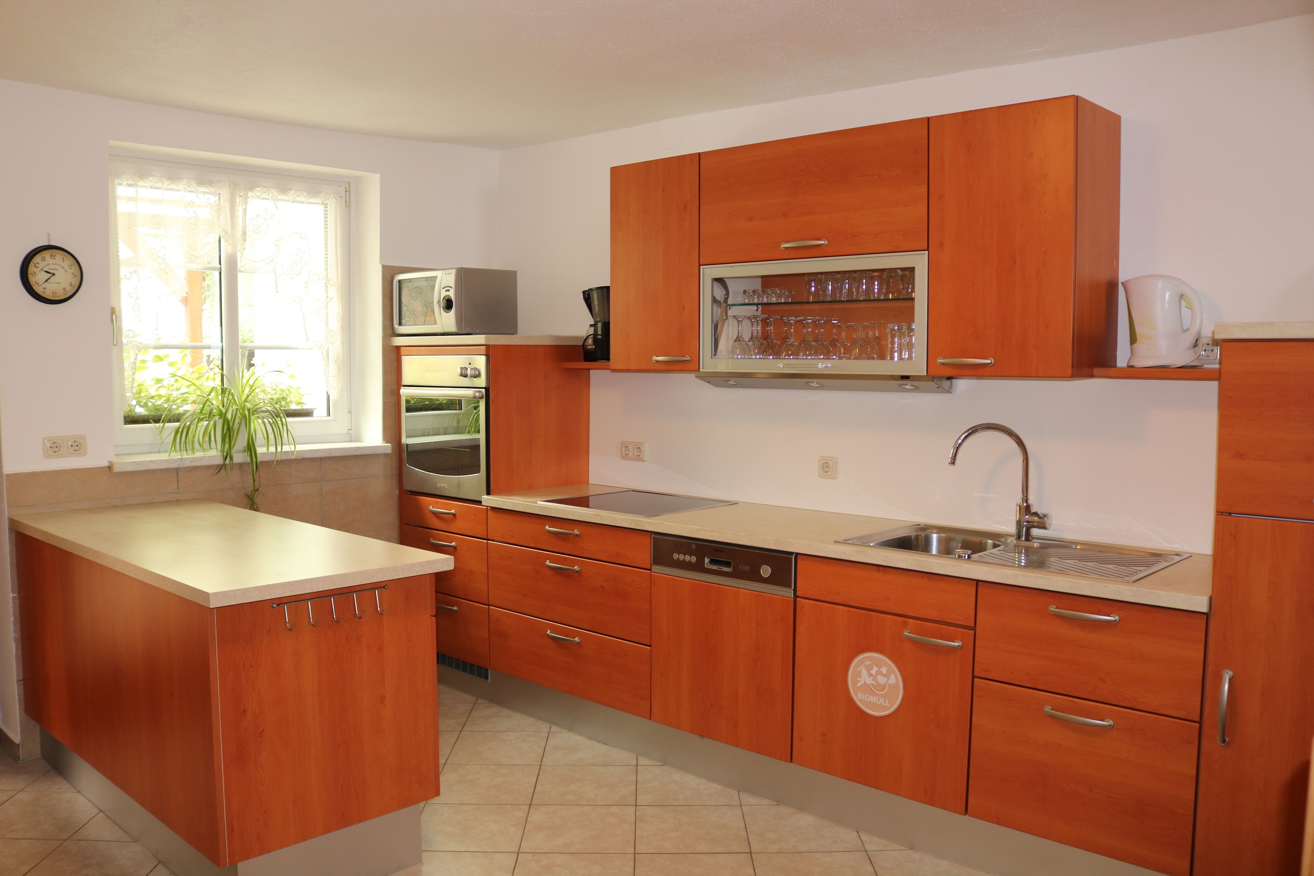 Modern kitchen with wooden cupboards, sink, stove and microwave.
