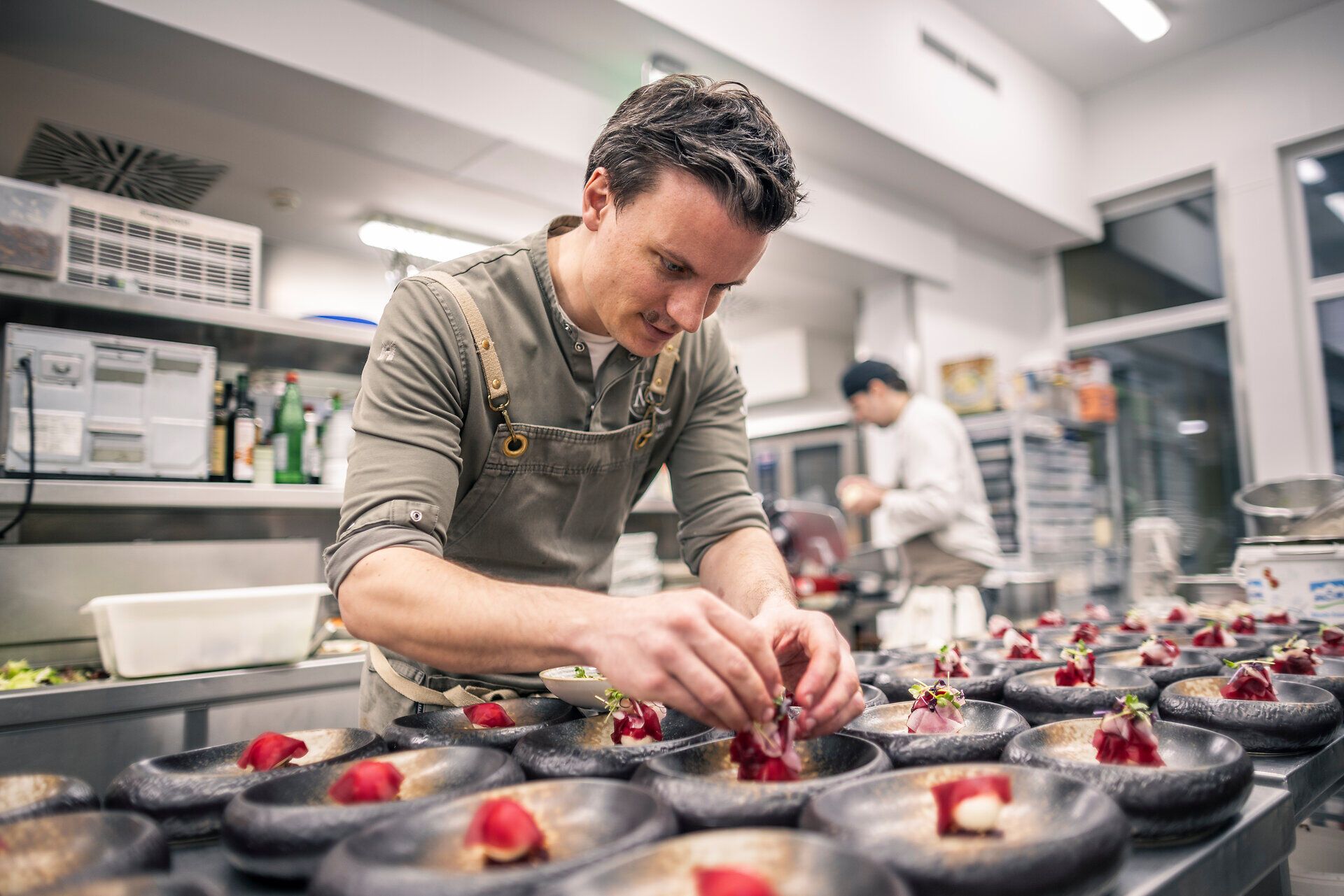 Chefkoch Peter Pichler steht in seiner Küche vom Hotel Molzbachhof. Vor ihm stehen viele angerichtete Teller.