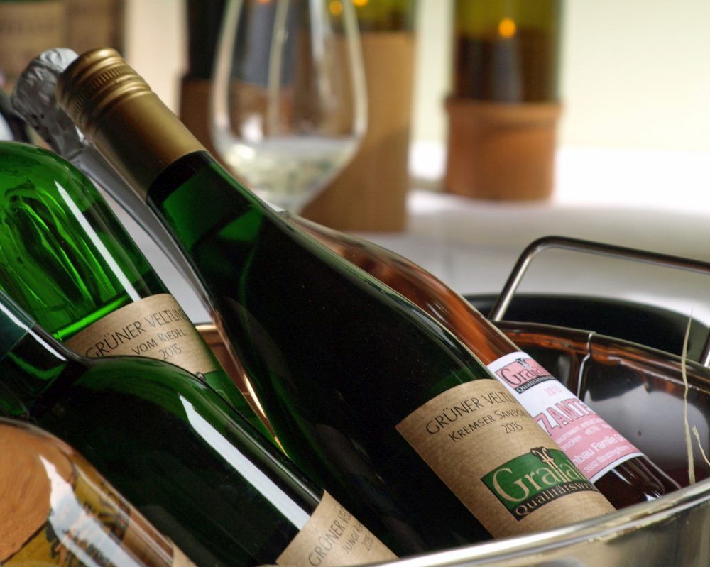 Close-up of wine bottles in a basket, a wine glass in the background.
