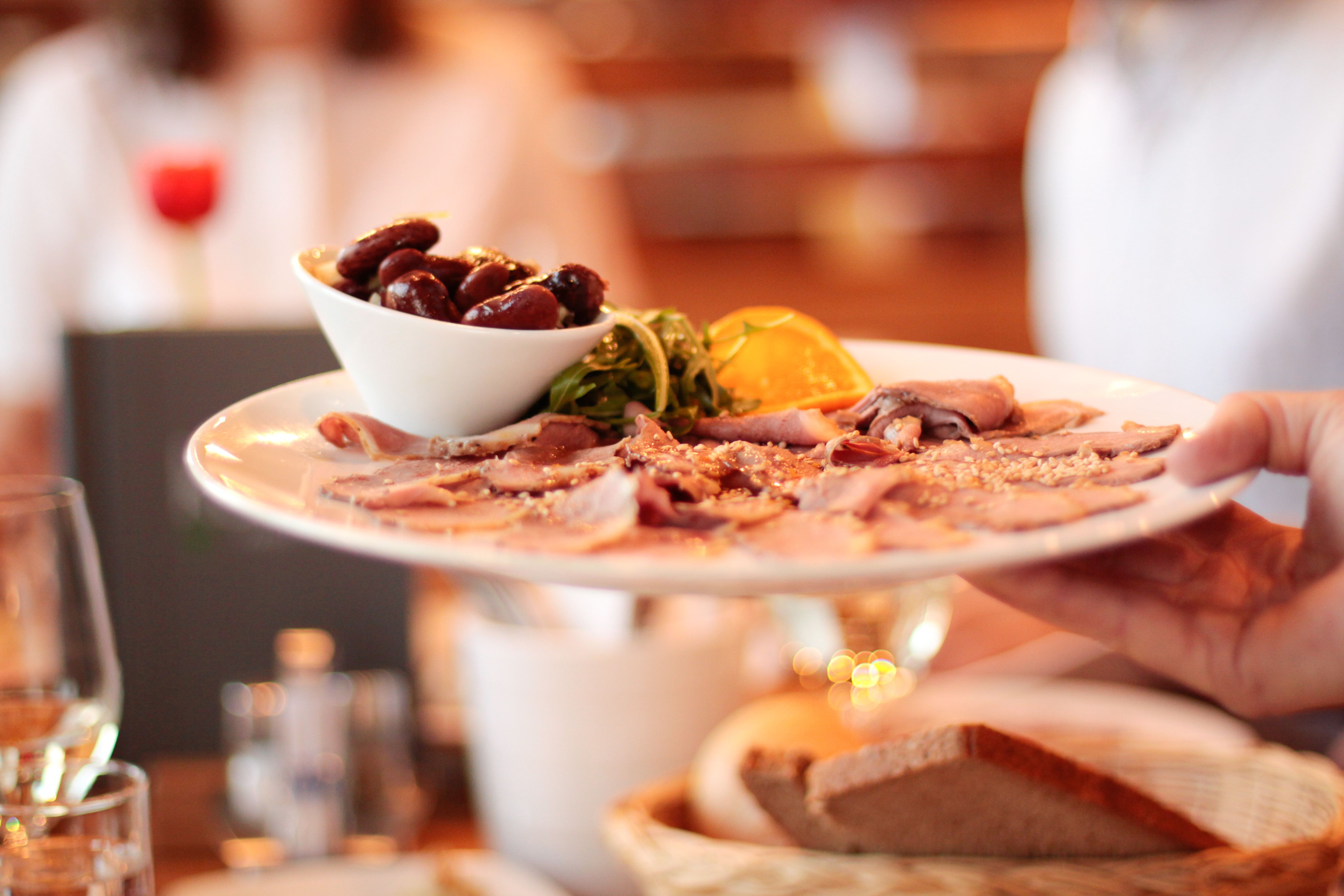 A plate of cold cuts and olives is served in a restaurant.