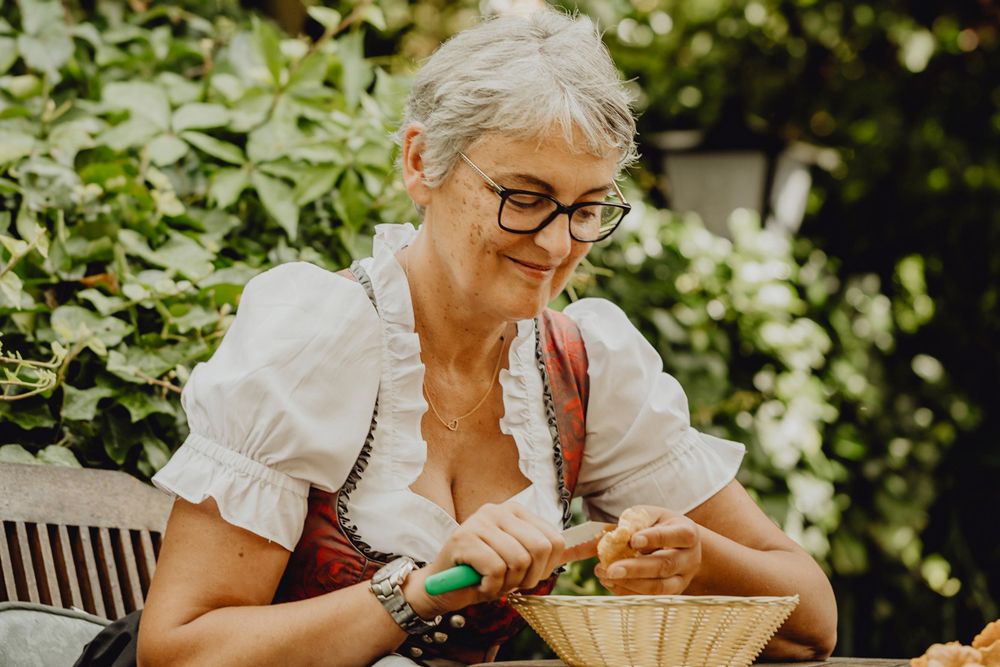 Woman in traditional dress cleaning mushrooms outdoors.