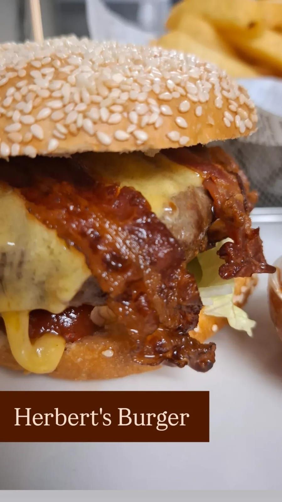 Close-up of a burger with sesame bun, melted cheese and crispy bacon.