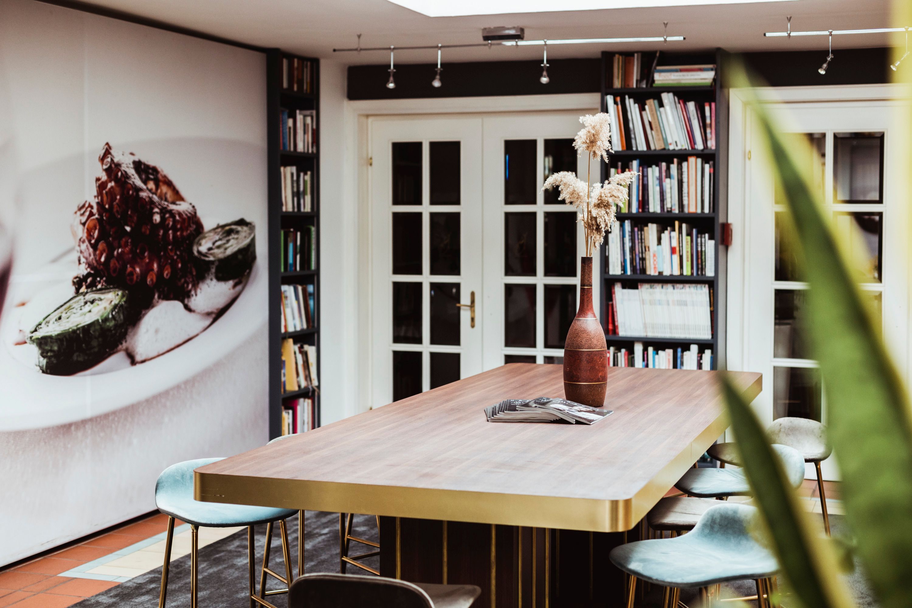 Modern room with large table, bookshelves and mural.
