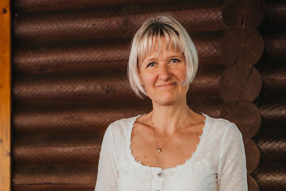Woman with blonde hair in front of a wooden wall