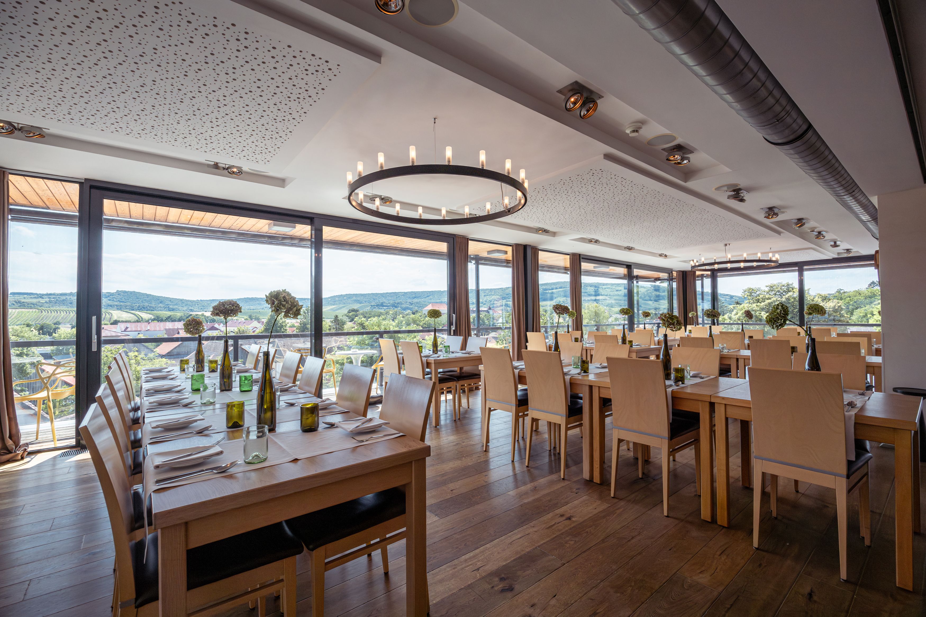 Interior view of a modern restaurant with large windows and a view of vineyards.