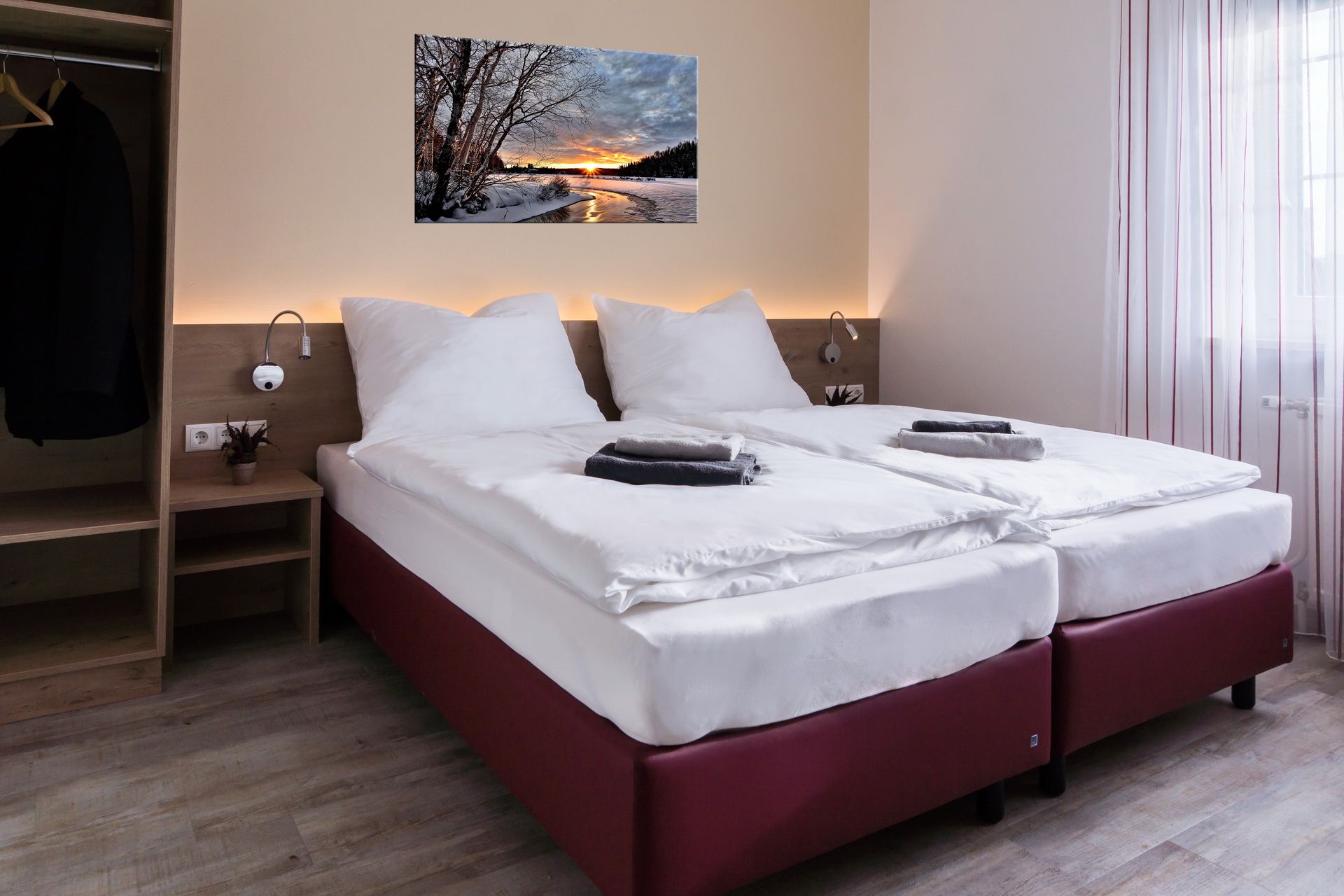 Modern double room with two single beds, picture on the wall, closet and window with curtains.