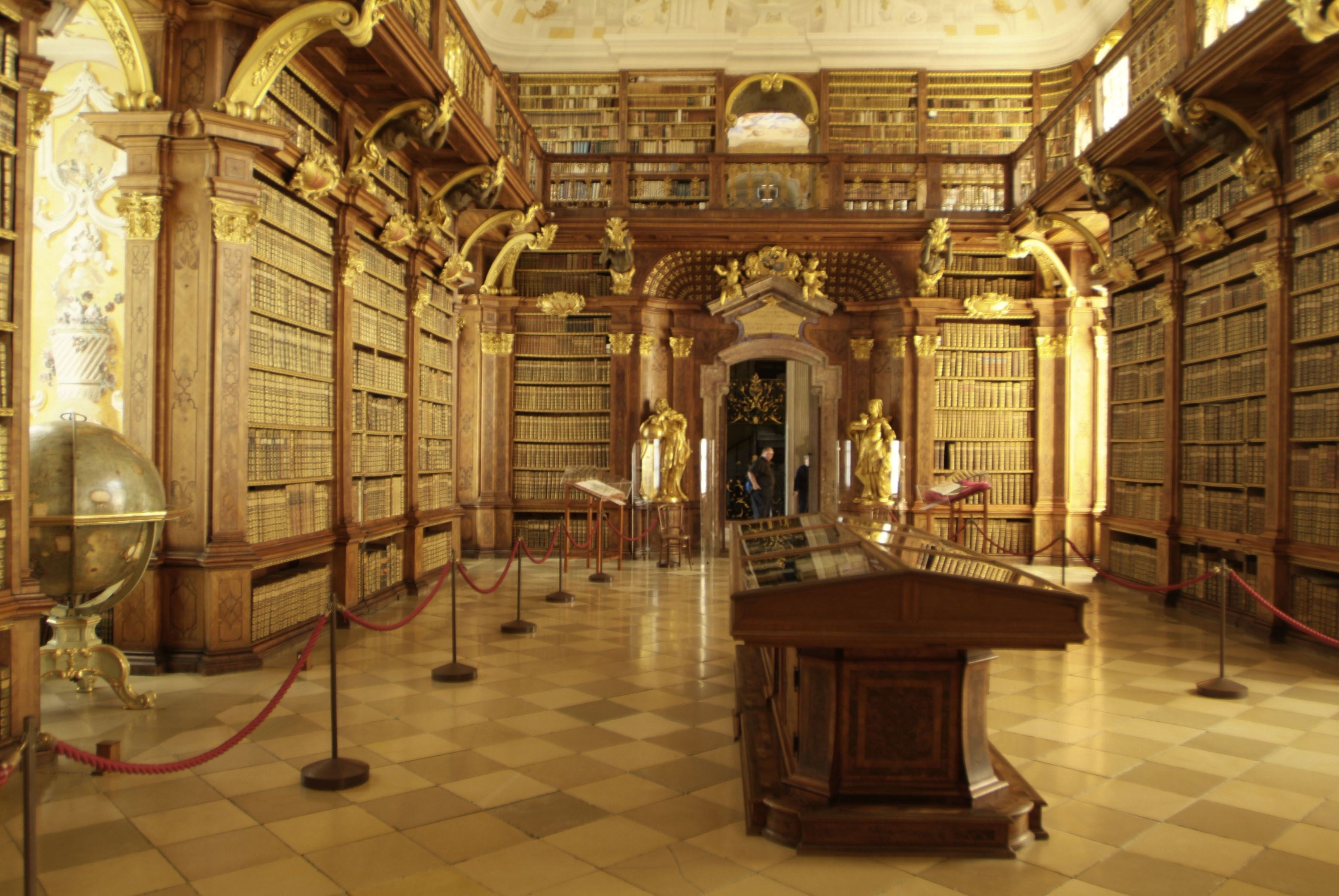 Interior view of the library in Melk Abbey with high bookshelves and golden decorations.