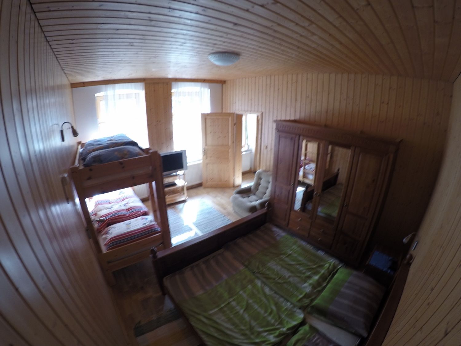 Wood-paneled bedroom with bunk bed, double bed, closet and TV.