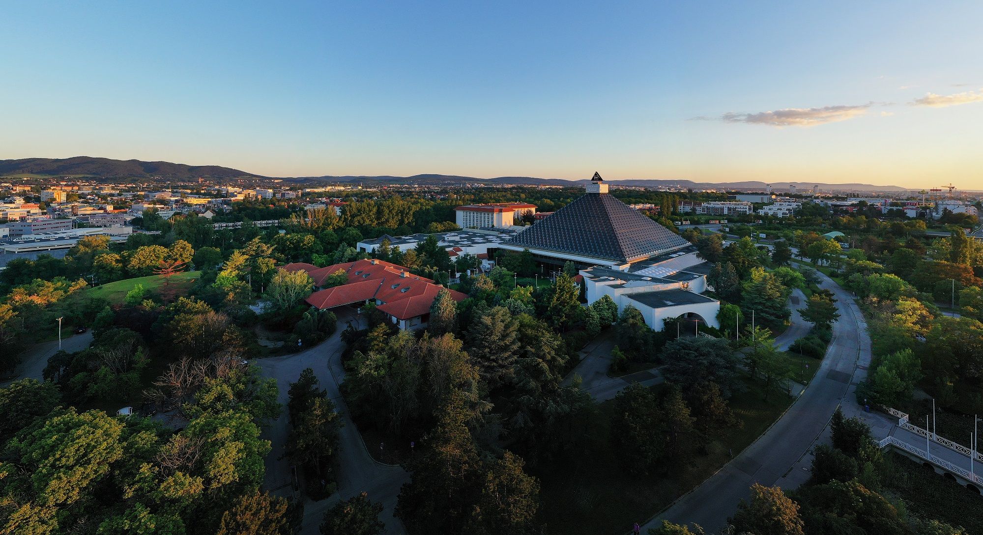 Aerial view of the Eventhotel Pyramide with the surrounding landscape at sunset.