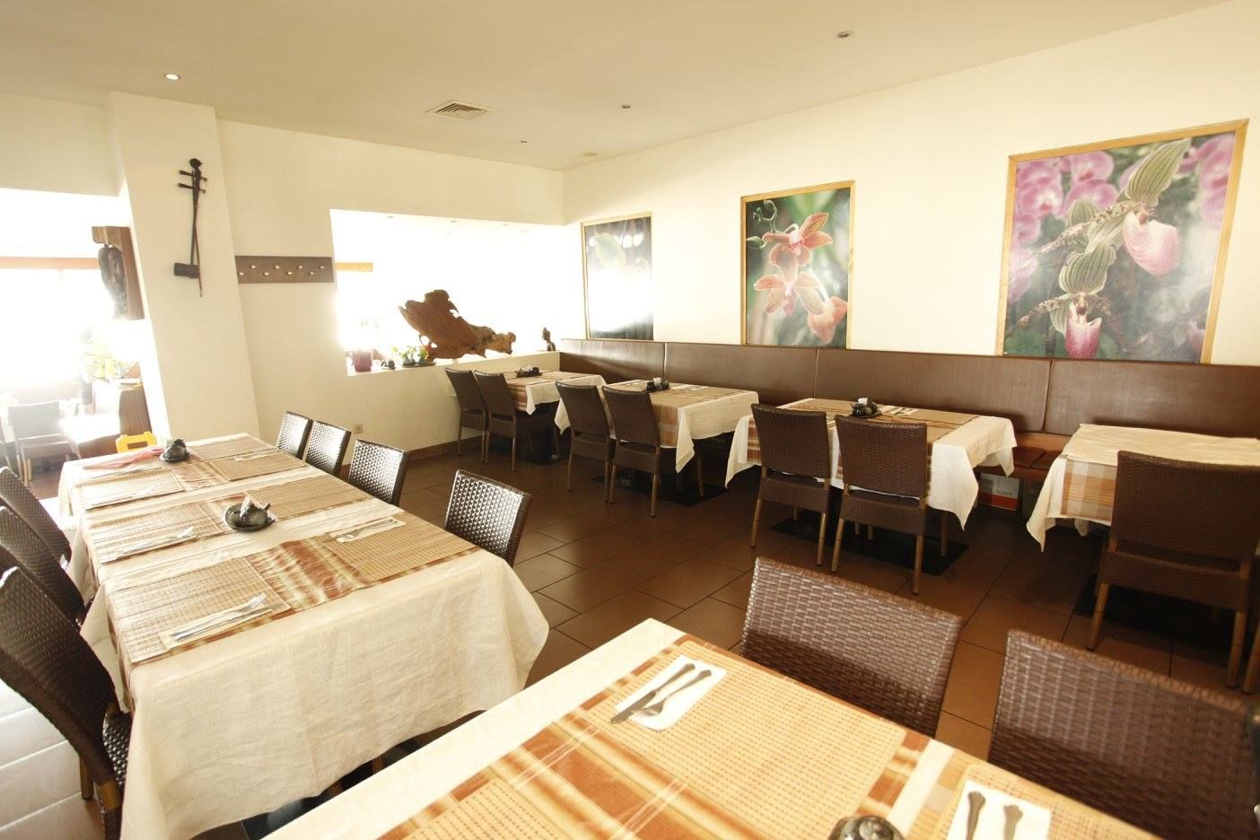 Interior view of a restaurant with laid tables and flower pictures on the wall.