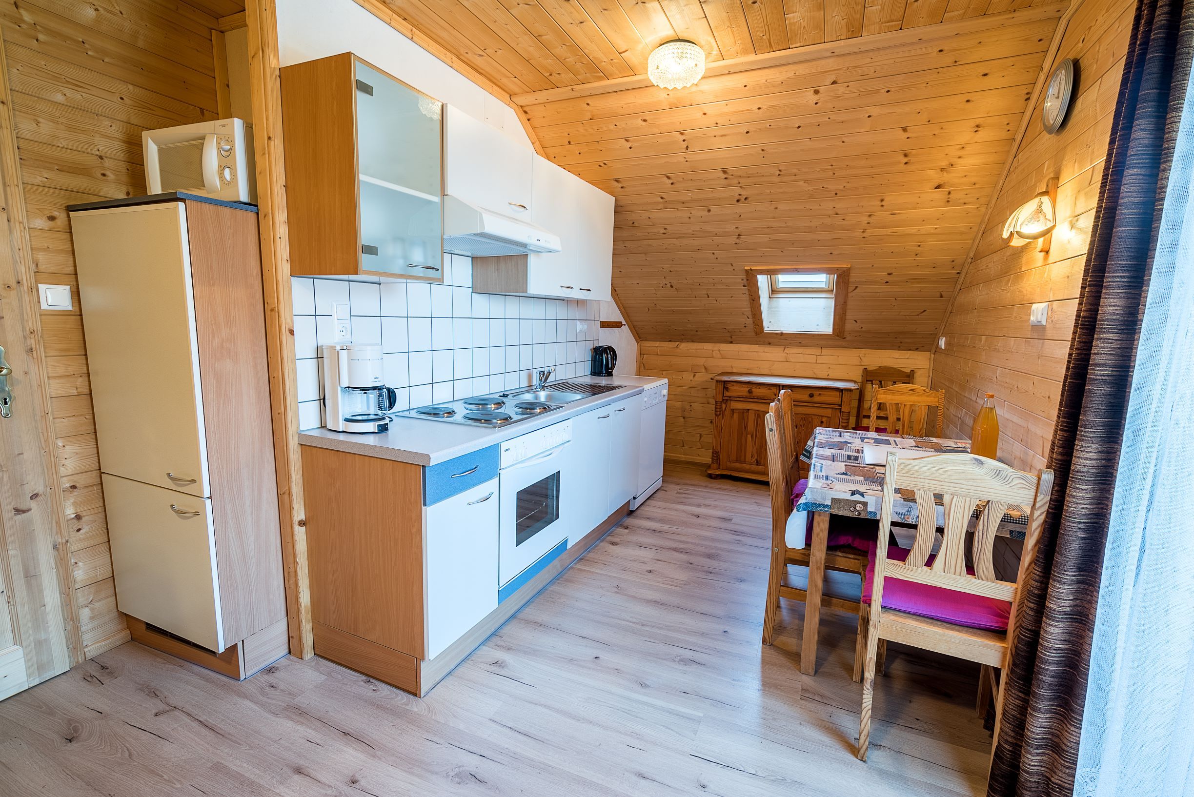 Kitchen with wood paneling, dining table and kitchenette.