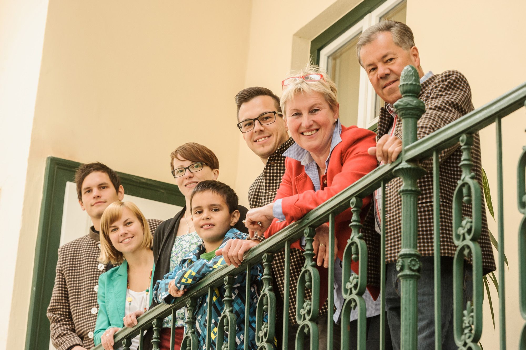The Gurtner family stands smiling by a green railing on a balcony.