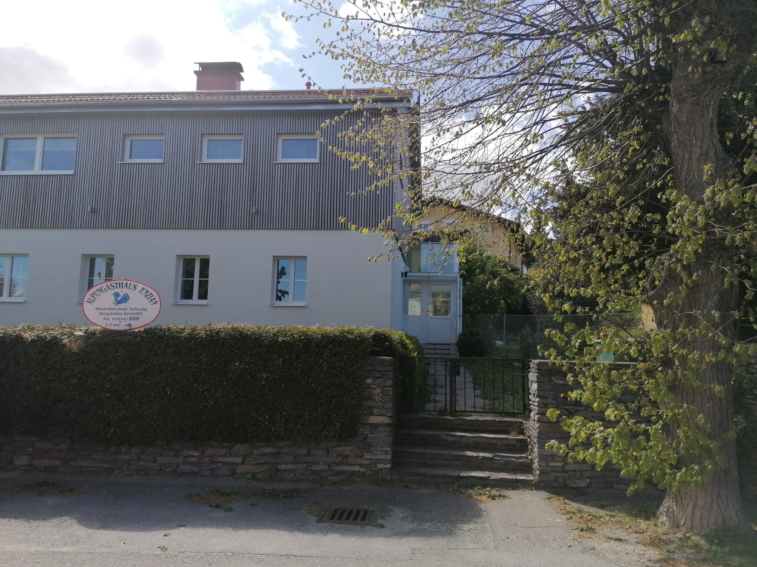 Two-storey building with sign 'Alpengasthaus Ewin' and garden.