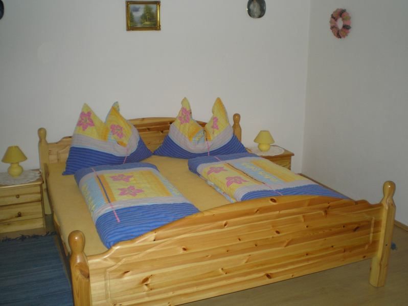 Wooden bed with colorful bedding in a bedroom.
