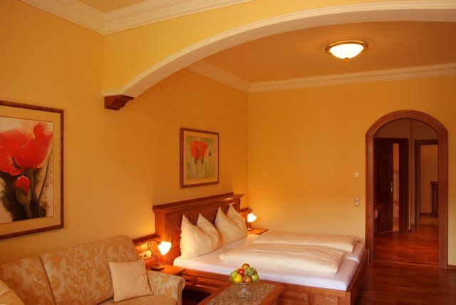 Cozy hotel room with double bed, sofa and paintings on the walls.