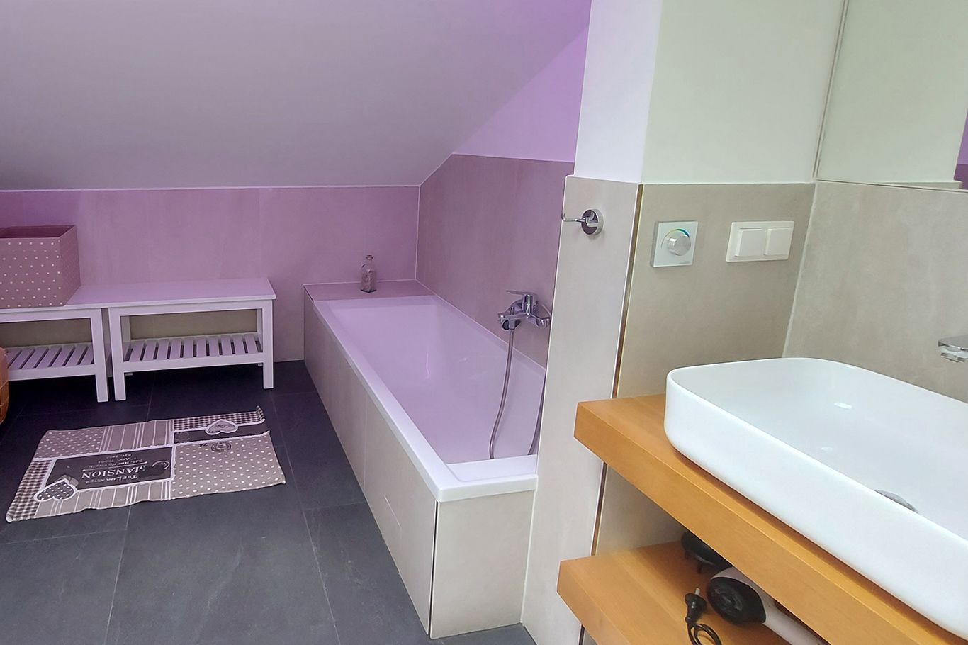 Modern bathroom with bathtub, washbasin and storage space.