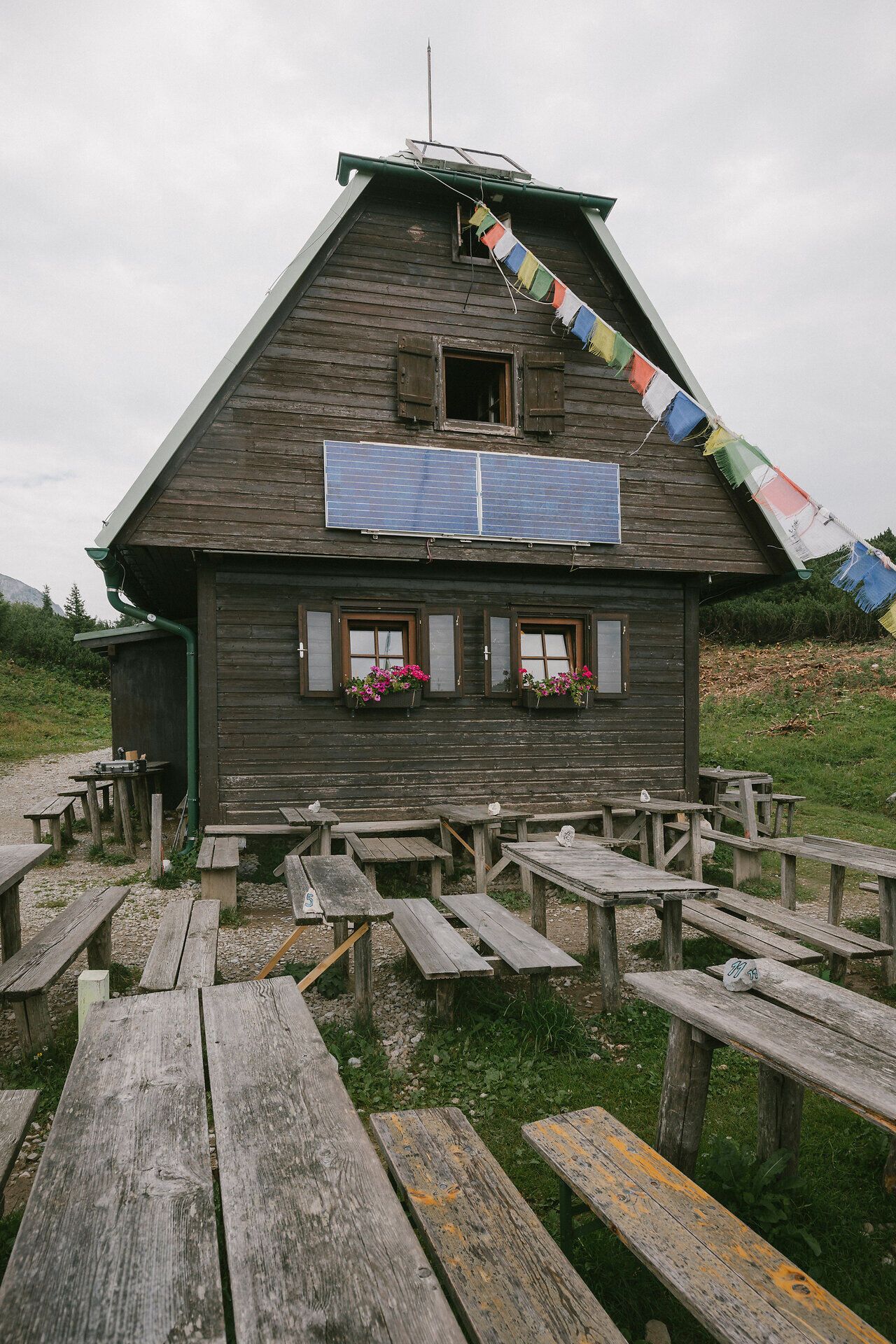 New lakeside cabin on the Rax with wooden benches and tables in front of the building