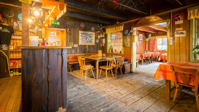 Interior view of a rustic hut with wooden furniture and decorations.