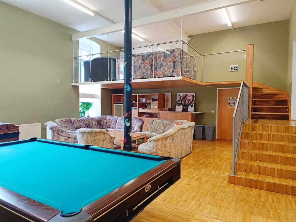 A youth room with a pool table, sofas and a gallery with stairs.