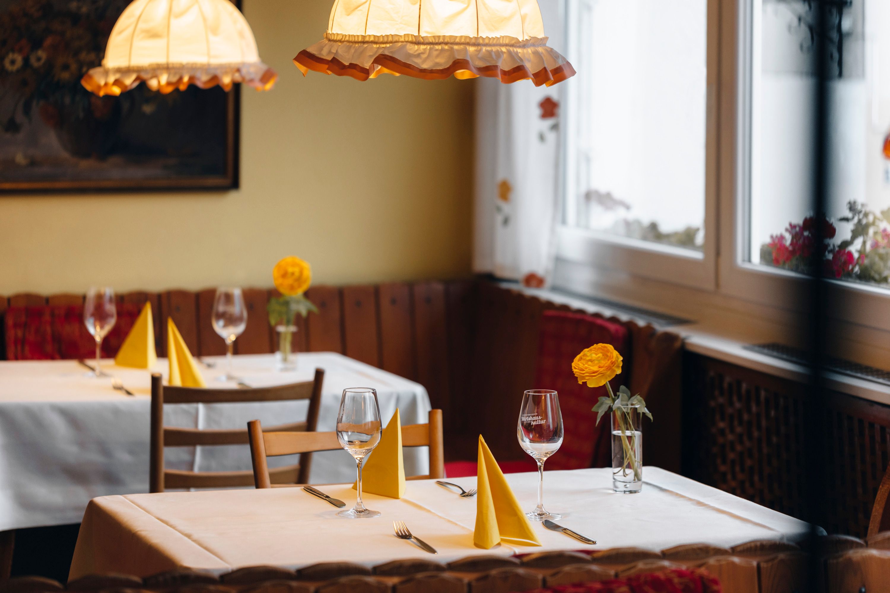 Cozy restaurant with laid tables, yellow napkins and flowers.