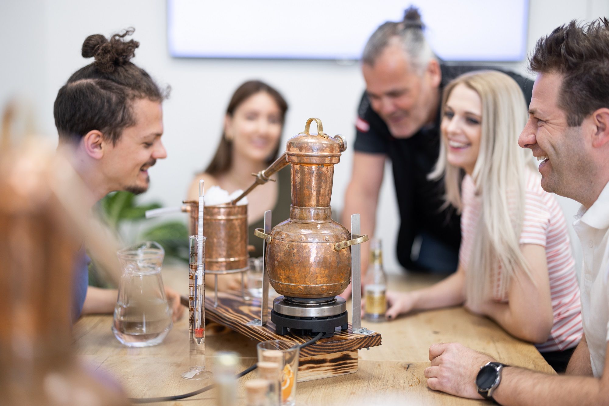 Group of people distilling schnapps with a copper still.