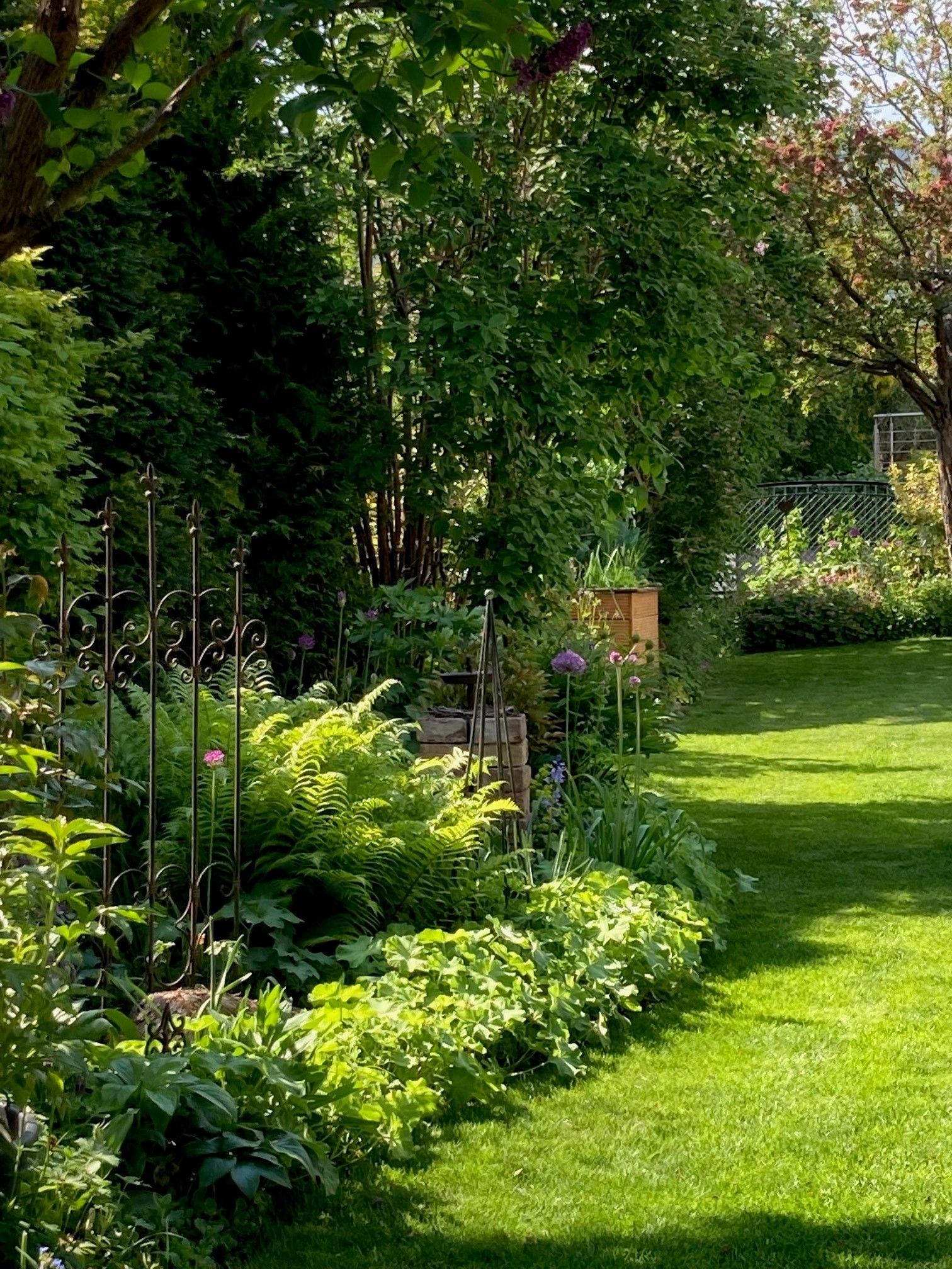 A well-kept garden with lush greenery, flowers and a small fence.