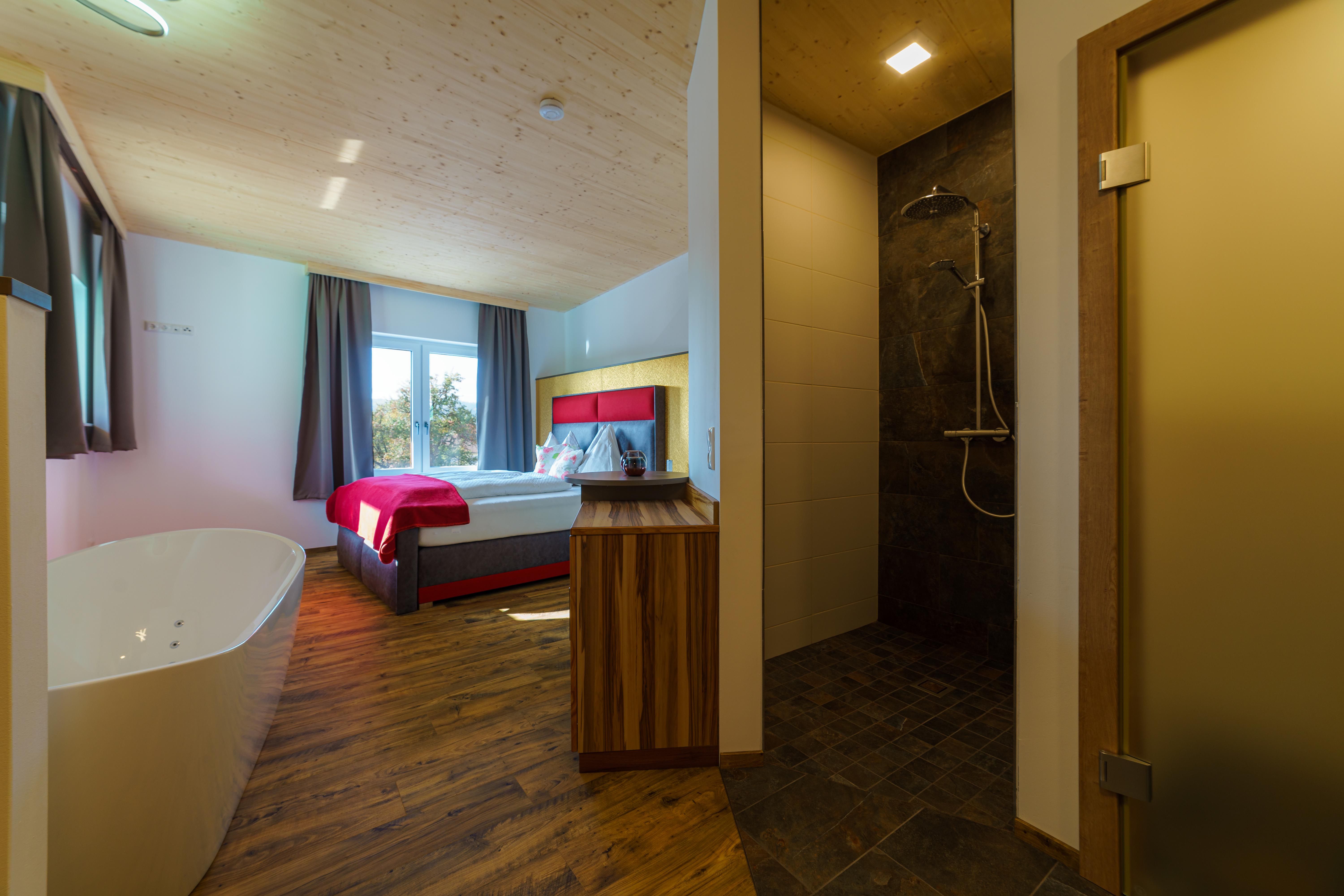 A cozy room with double bed, free-standing bathtub and modern shower.