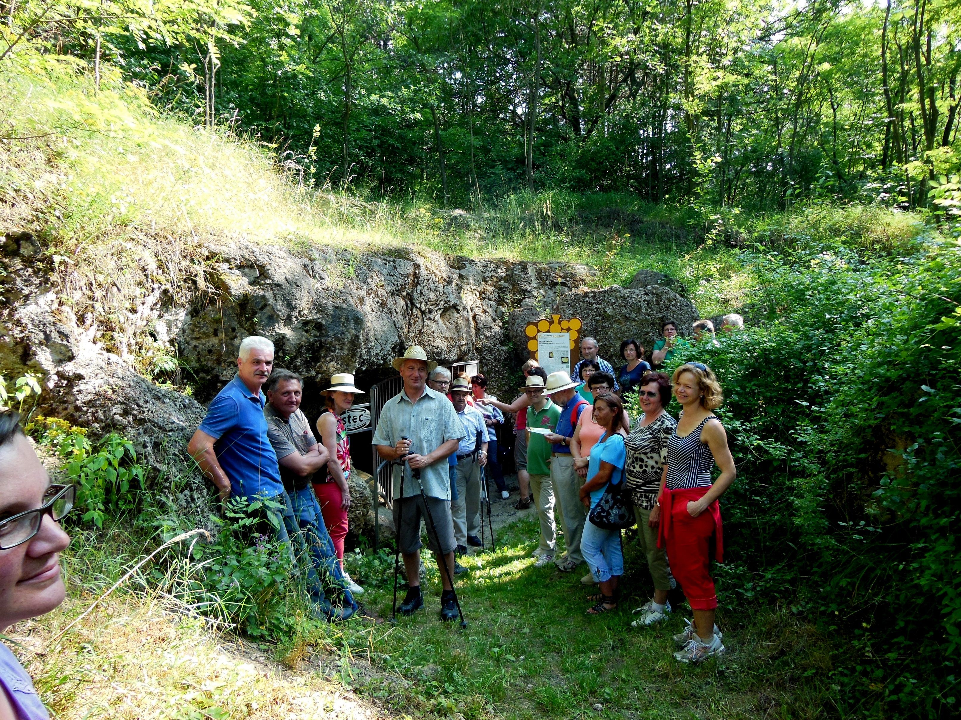 Group of people in front of a cave in the countryside.