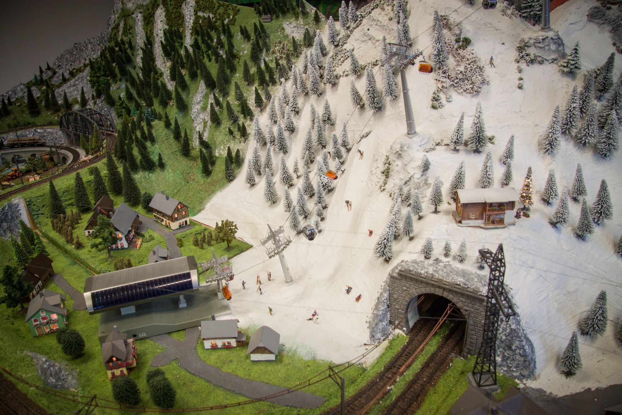 Model landscape with mountains, skiers, cable car and railroad tunnel.