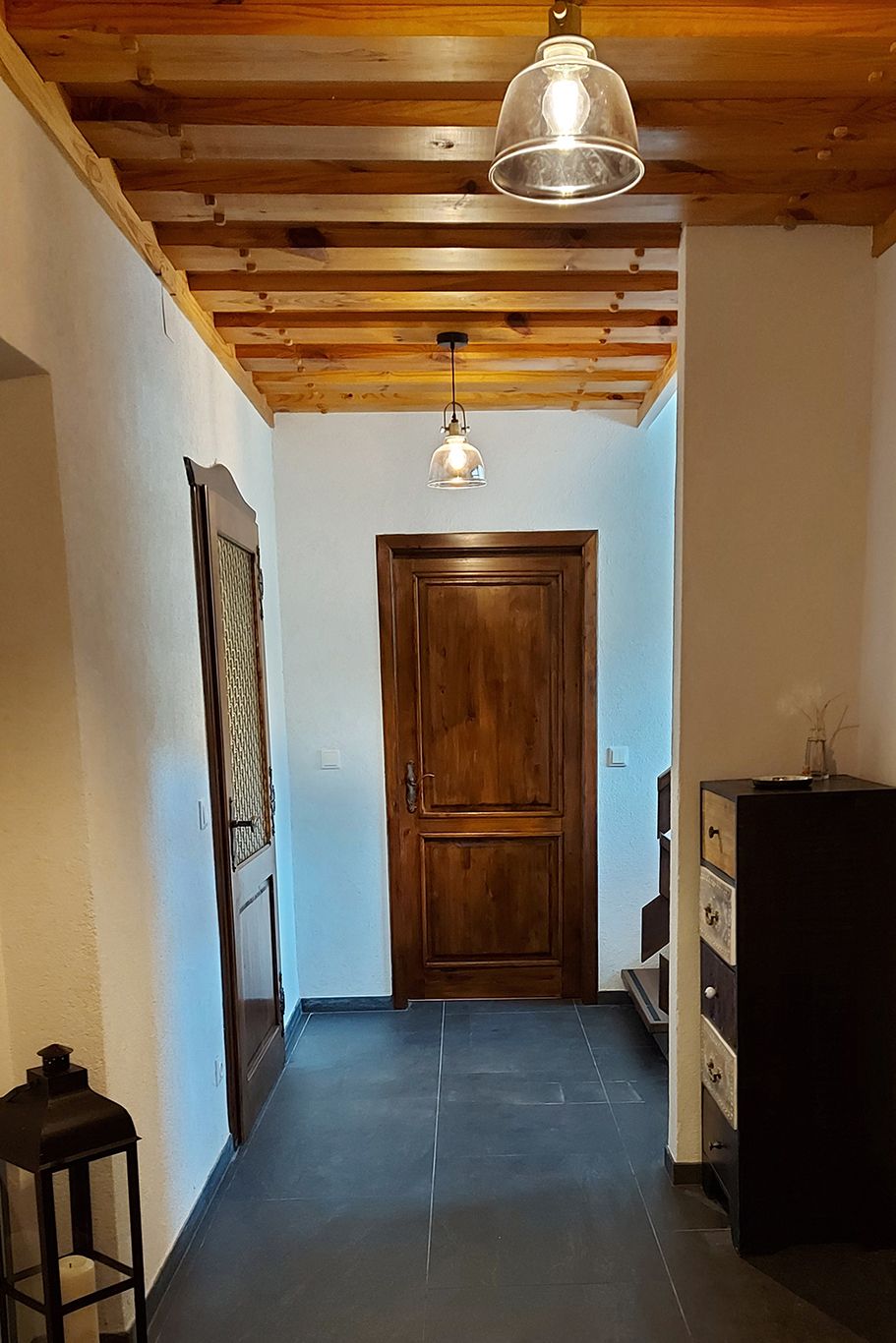 A hallway with wooden doors, wooden ceiling and modern lamps.