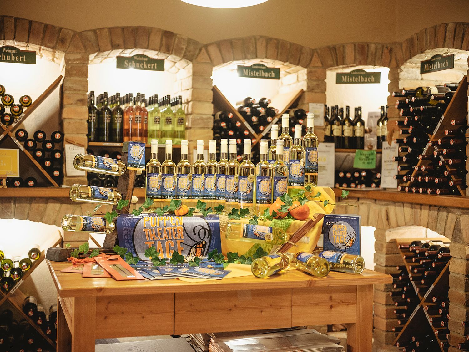 Wine racks in a wine cellar with bottles and decoration on a table.