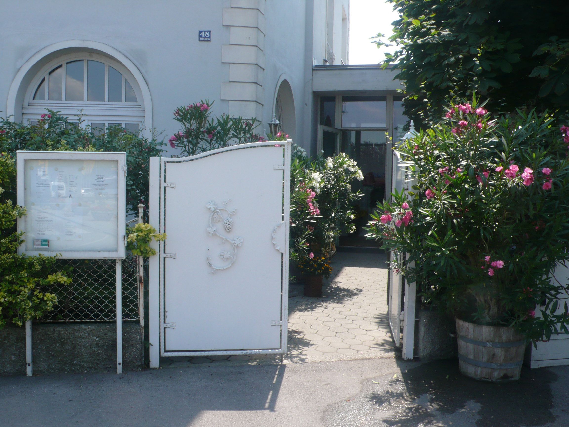 Entrance with white gate and flowering oleander plants.