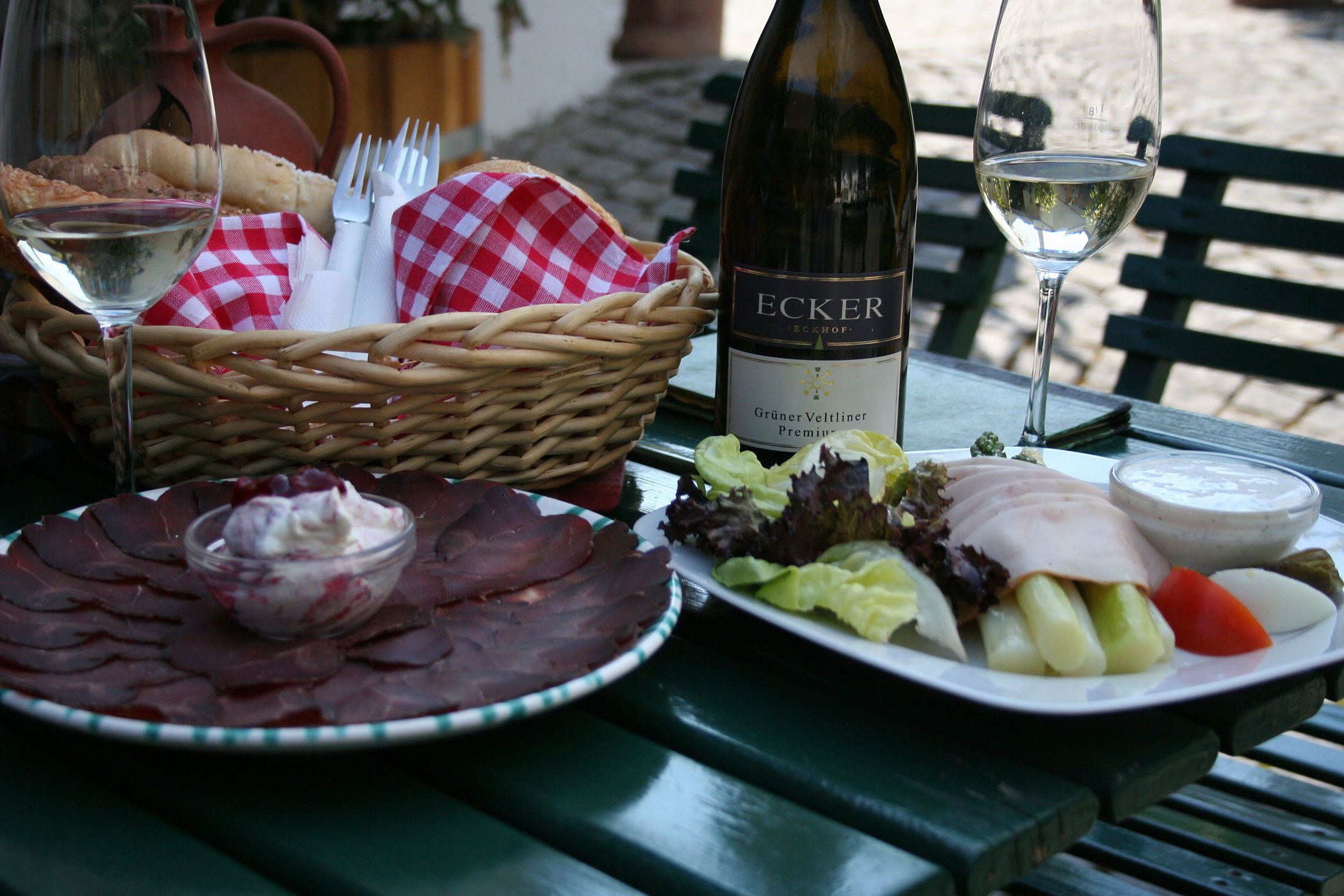 A laid table with wine, bread, cold cuts and salad.