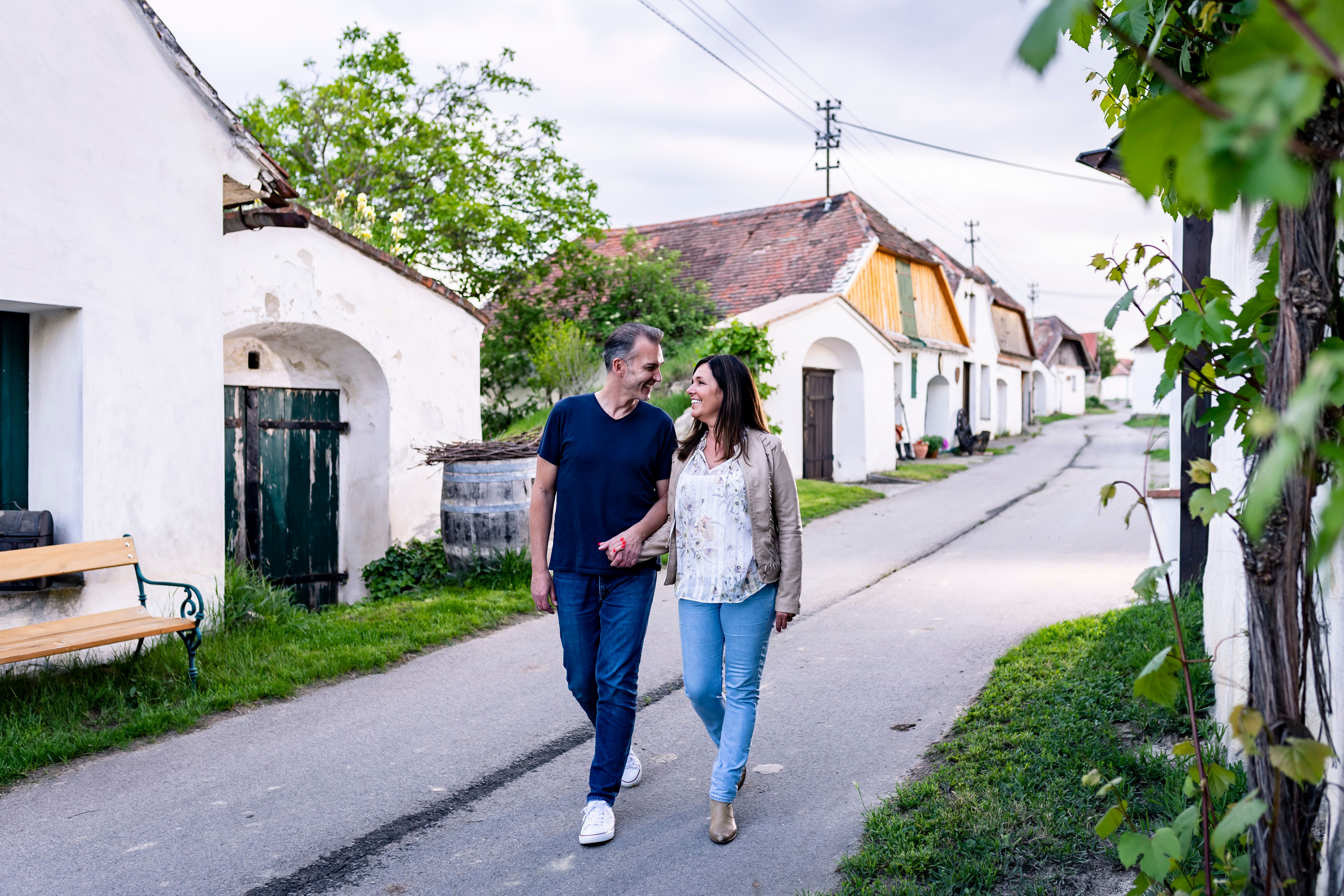 A couple walks through the wine cellar lane in Zellerndorf, surrounded by traditional wine cellars.