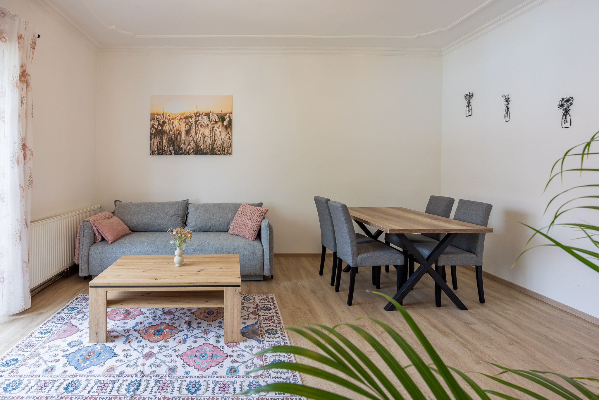 Living room with gray sofa, wooden table, carpet and dining table with chairs.